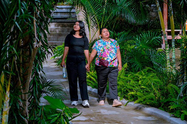 istock Two Women Walking Hand in Hand in Lush Garden Pathway 2202607313