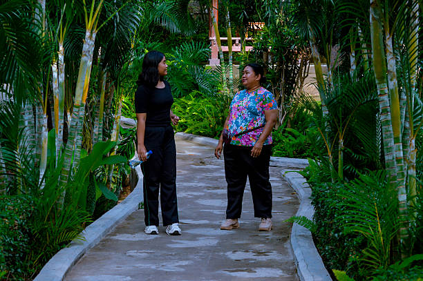 istock Two Women Walking and Conversing in a Lush Garden Path 2202607340