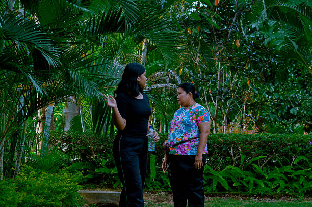 istock Two Women Conversing in a Lush Green Garden with Trees 2202607379