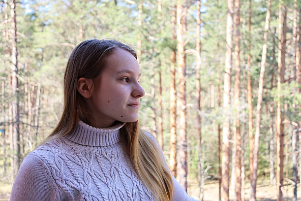 Young woman in a beige sweater and blond hair smiling