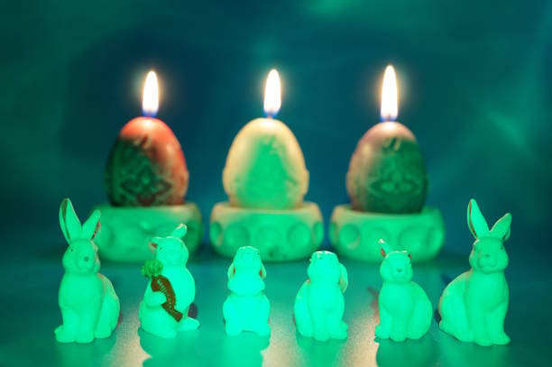 Toy bunnies and burning Easter candles on a blue background.