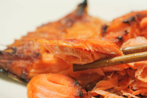 Trying to eat grilled salmon with chopsticks.