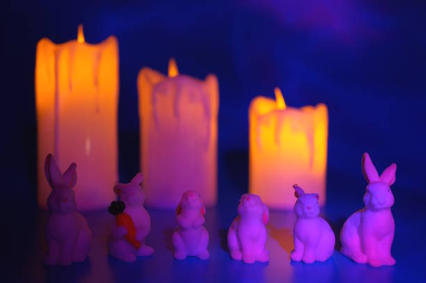 Toy rabbits and burning candles on a blue background.