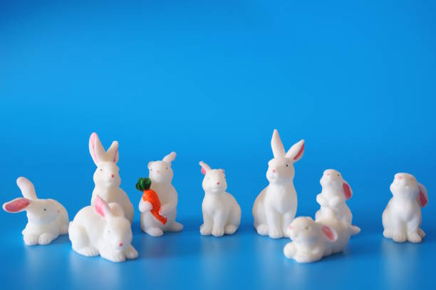 istock Toy white hares on a blue background. Animal figurines. 2202619624