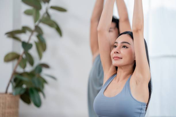 istock Yoga practitioners engage in a stretching routine in a bright indoor space surrounded by greenery 2202623429