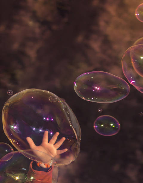 istock A close-up of a child's hand playing with bubbles 2202629008