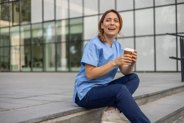 istock Smiling doctor drinking coffee during break outside hospital 2202632197
