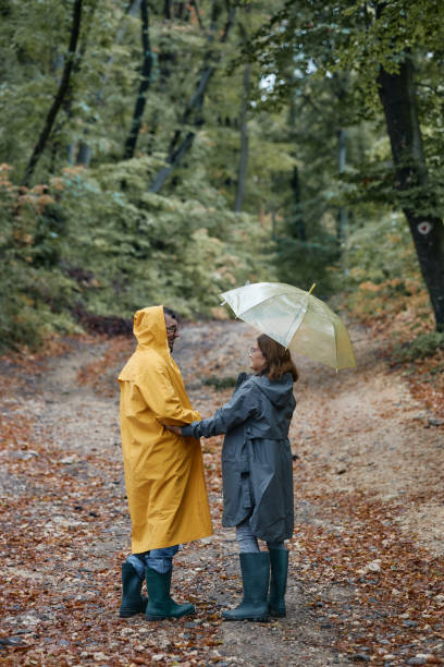 istock Happy embraced senior couple walking with umbrella at forest 2202635497