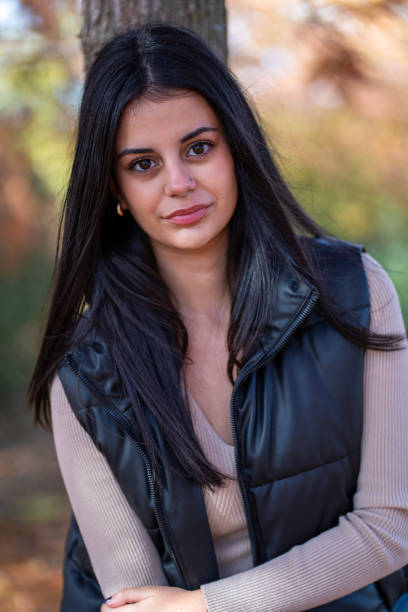 istock Young woman leaning against tree in autumn park 2202635705