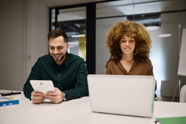 istock Smiling business people working together in modern office using digital tablet and laptop 2202638069