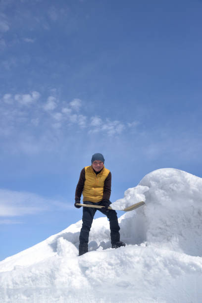 istock An old man removing snow with a shovel 2202638749