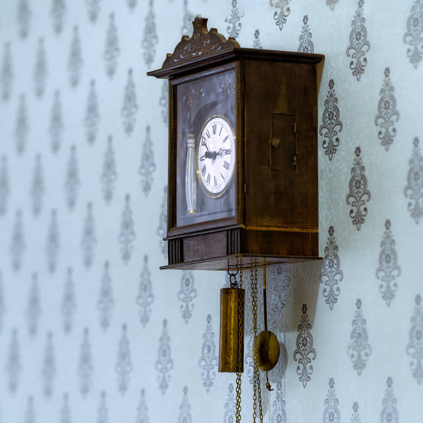 istock Antique wooden clock with a mechanical winding on the wall. 2202639338