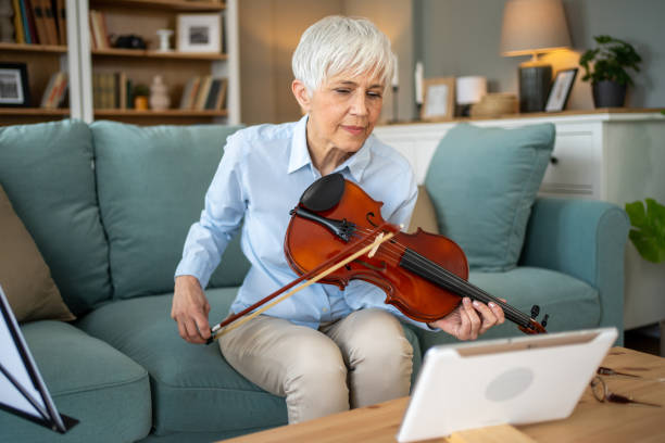 istock Senior woman playing violin during online class at home 2202639376