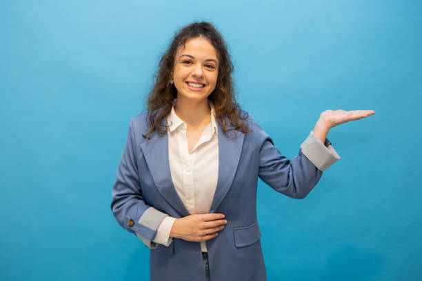 istock Young businesswoman showing something on blue background 2202640686
