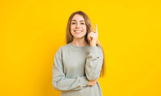 istock Young woman having an idea pointing upwards on yellow background 2202648303