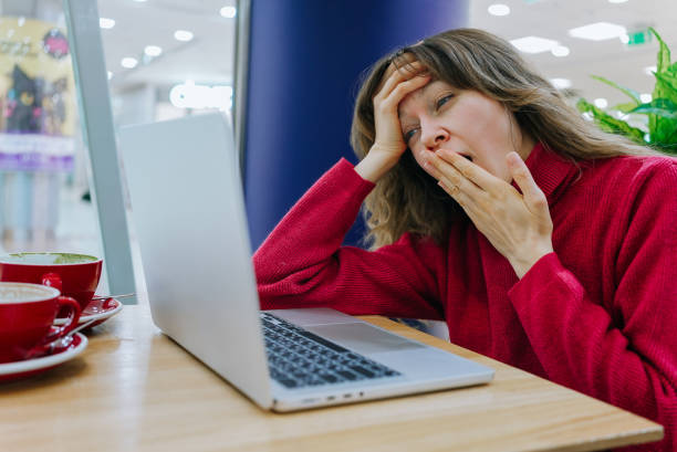 istock Tired freelancer yawning while working on laptop in cafe 2202653774