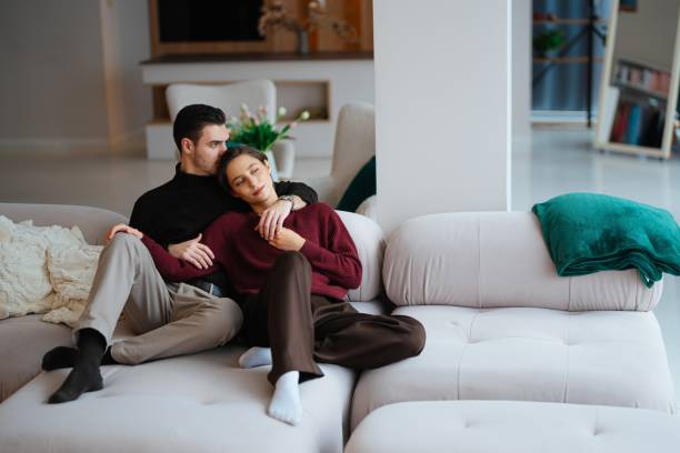 istock Cozy couple relaxing together on a comfortable couch at home 2202654334