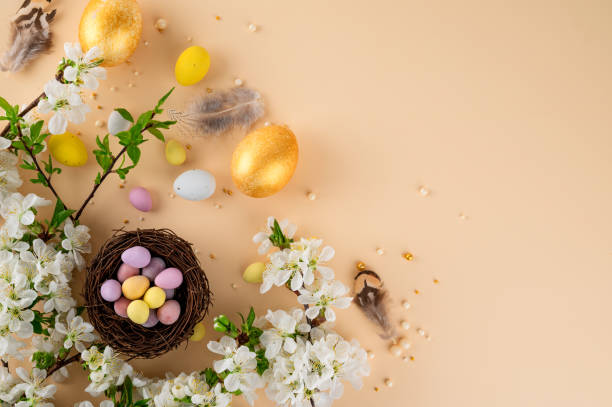 istock Easter Sweet Composition with Decorative Nest, Chocolate Eggs, Colorful Sugar Sprinkles and Blossoming Branch on Pastel Background. Top view, copy space. 2202655240