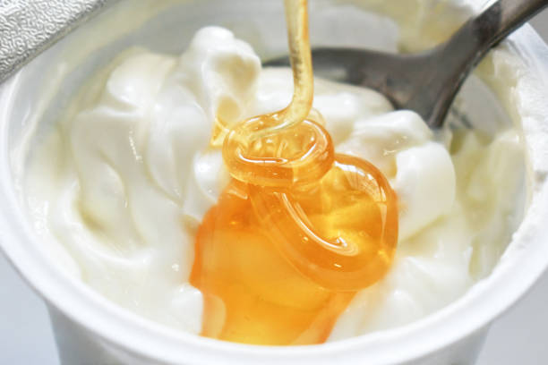 istock Pouring honey syrup on greek yogurt pot. 2202662708