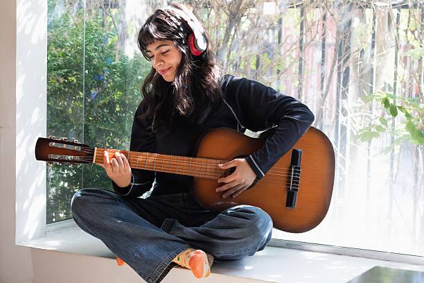 istock teenage girl practicing guitar with her left hand 2202663373
