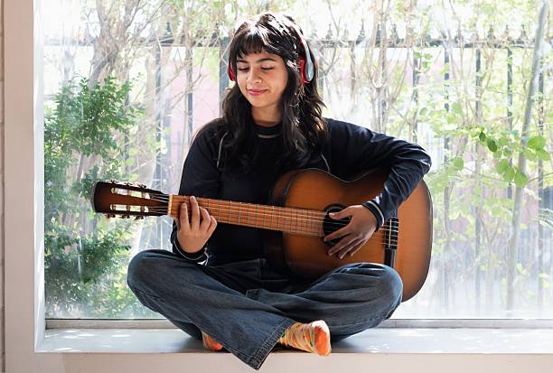 istock young latina woman practicing guitar with left hand 2202663489