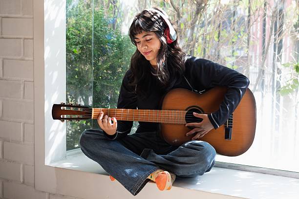 istock left-handed woman practicing a song with her guitar 2202663514