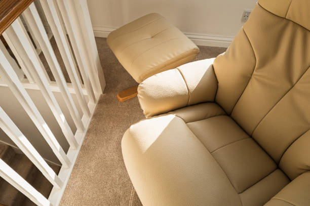 Luxury leather armchair and matching footstool seen on a first floor loft conversion in a show home. Part of the stairwell can be seen.