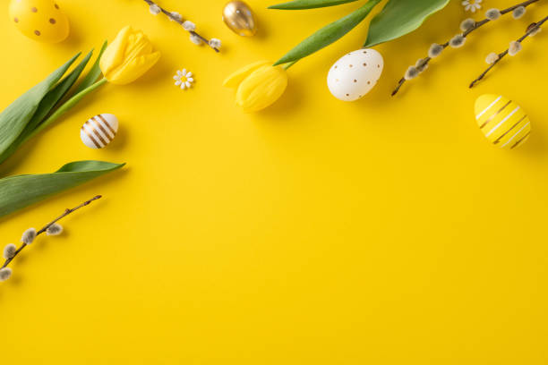 istock Vibrant festive Easter decoration featuring yellow tulips, colorful eggs, and floral branches on a yellow surface creating a cheerful springtime mood 2202668704