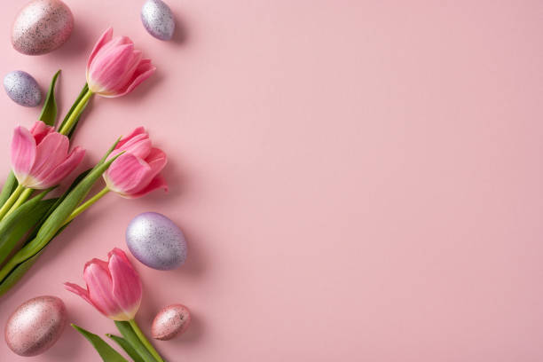 istock Decorative arrangement with pink tulips and colorful eggs on pink backdrop, symbolizing Easter 2202668721