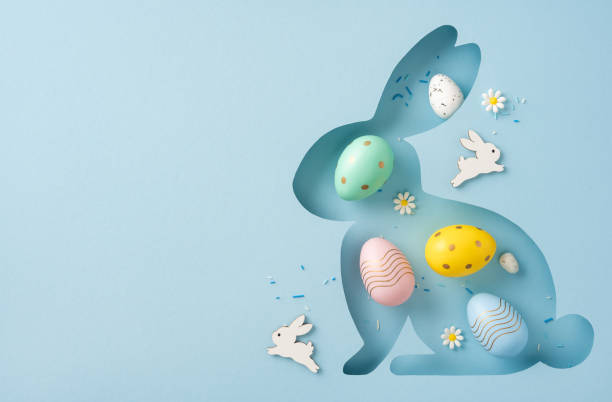 istock Stylized hollow Easter bunny silhouette filled with vibrant eggs and small white daisies on a clean, minimal blue background 2202668722
