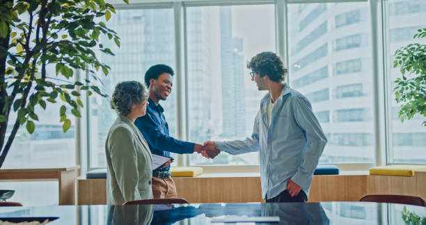 istock Diverse business team shaking hands celebrating successful agreement with smiles in modern office. Sustainable business and finance. 2202669810