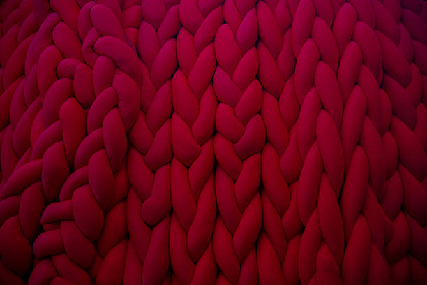 istock Knitted texture of deep red fabric creates a cozy atmosphere in indoor space 2202671426