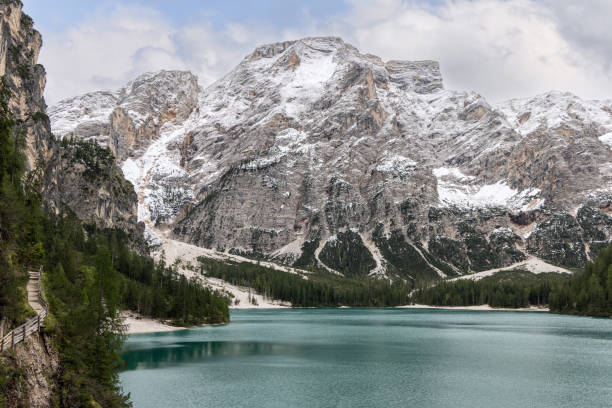istock Lake Braies with turquoise waters, a winding wooden path along the forested cliffs, and majestic snow-covered mountains forming a dramatic alpine landscape in South Tyrol Italy 2202677005