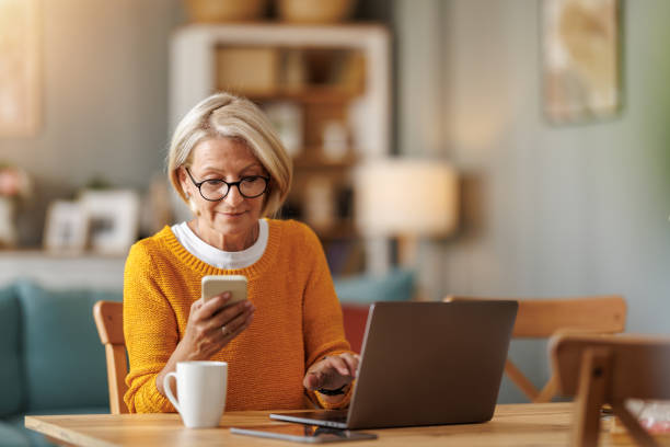 Senior woman engages in digital communication at home while enjoying coffee