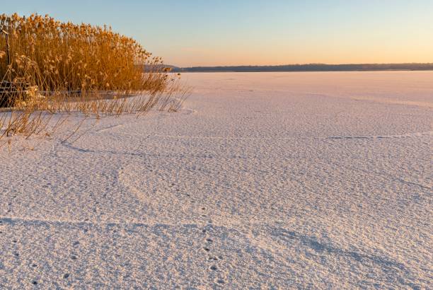 istock Snow-Covered Frozen Lake with Footprints in the Winter Sunlight 2202679897