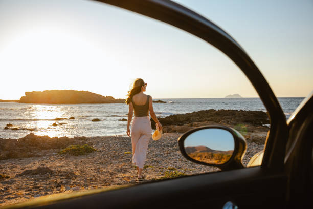 istock Woman enjoying a scenic coastal view through a car window during sunset 2202687026