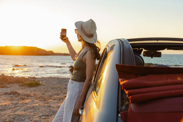 istock Woman enjoying a coastal sunset while capturing the view with her phone 2202687129
