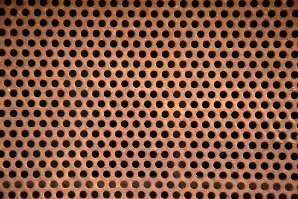 A detailed closeup view showcasing a perforated metal surface that features numerous black dots arranged uniformly throughout it