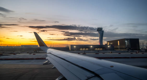 istock Airplane Wing View at Sunset with Airport Control Tower 2202691285