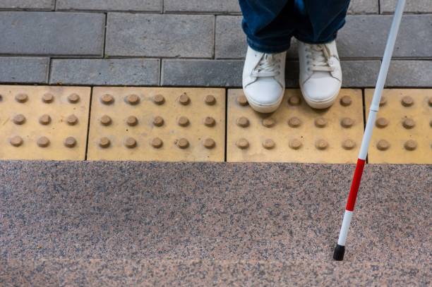 istock Blind woman walking outdoors using a tactile cane. 2202694330