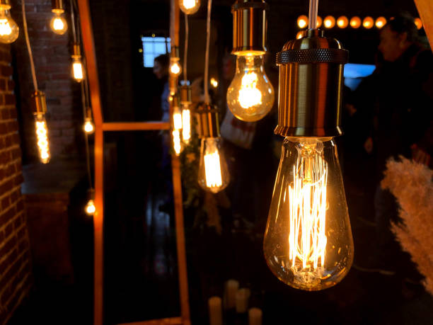 istock Warm lamps hang in a dark room and provide decorative light. 2202695608