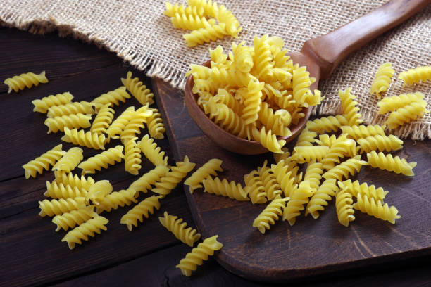 istock Rotini Pasta. Spiral pasta in a wooden spoon on the table 2202695998