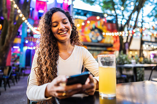 istock Young woman using mobile phone in a bar 2202696996