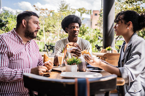 istock Coworkers talking and eating in a coffee shop 2202697324