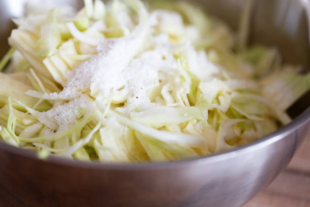 Close-up of white cabbage, covered with salt, which is about to be kneaded into the vegetable, starting the fermentation process
