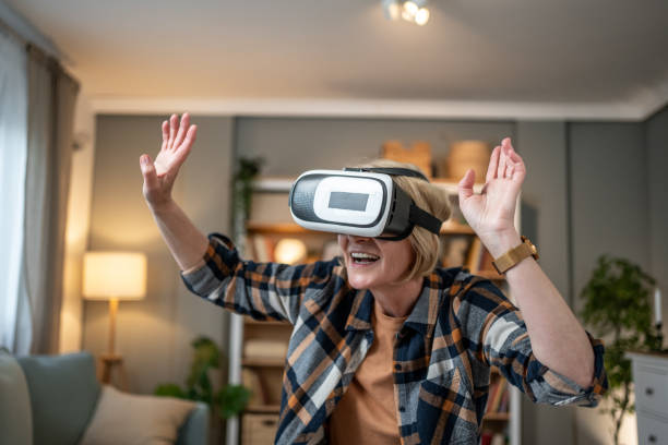 istock Senior woman exploring virtual reality at home, enjoying immersive experience 2202705889