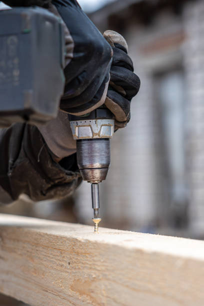 istock Gloved Hand Using Power Drill to Drive Screw into Wooden Plank 2202712277