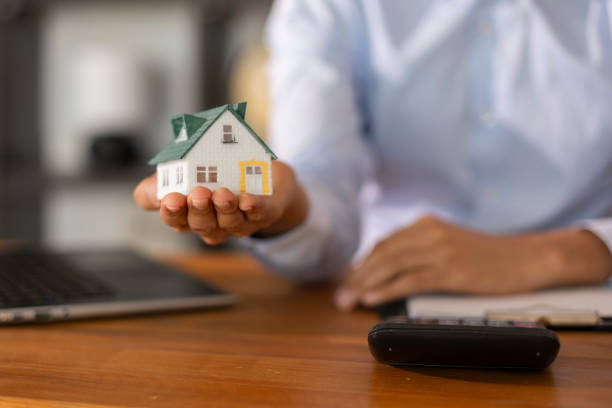 istock Real estate agent presenting a small house model in an office setting 2202712389