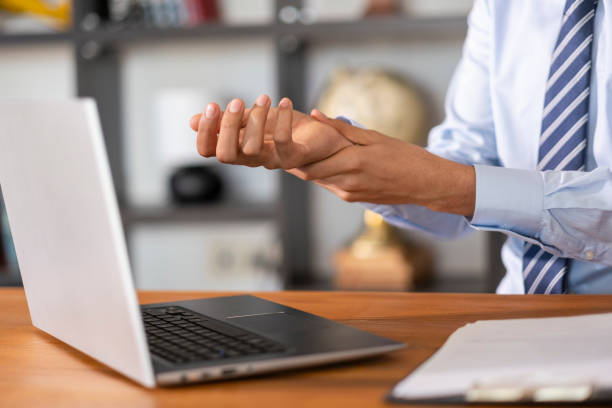 istock Office worker suffering from wrist pain while working on a laptop 2202713461