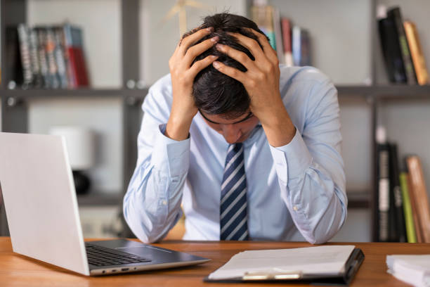 istock Businessman suffering from stress and headache while working on laptop at office 2202713728